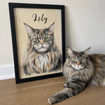 Long-haired tabby cat lying beside a framed custom watercolor pet portrait personalized with the name Lily.