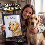 A woman sitting on a couch with a yellow Labrador Retriever holds up a framed custom pet portrait of the dog named Duke. The portrait shows a detailed sketch-style drawing of the dog in golden yellow and brown tones.